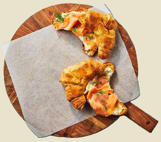Smoked salmon croissants on a wooden serving board